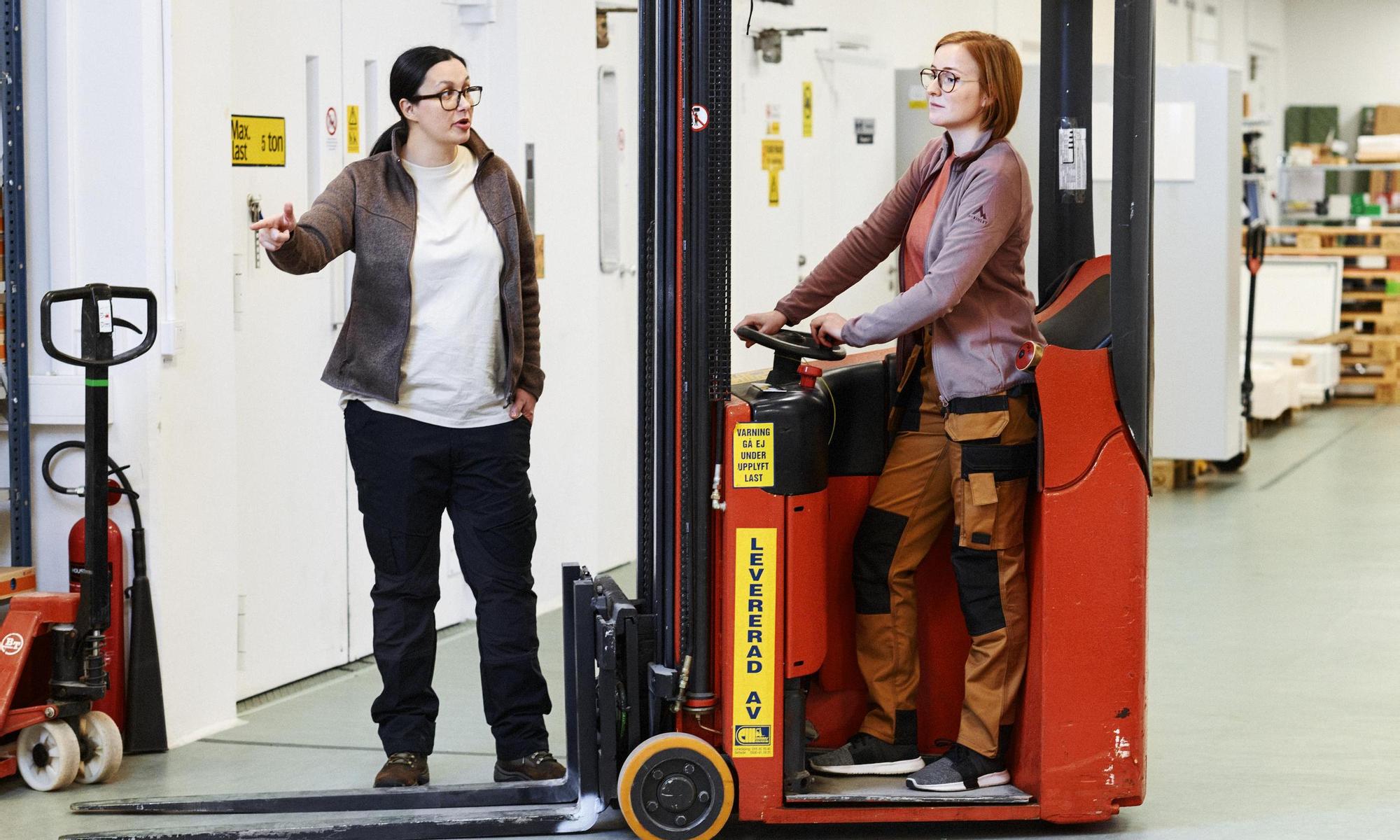 Two women collaborate - one driving a truck and the other pointing the direction