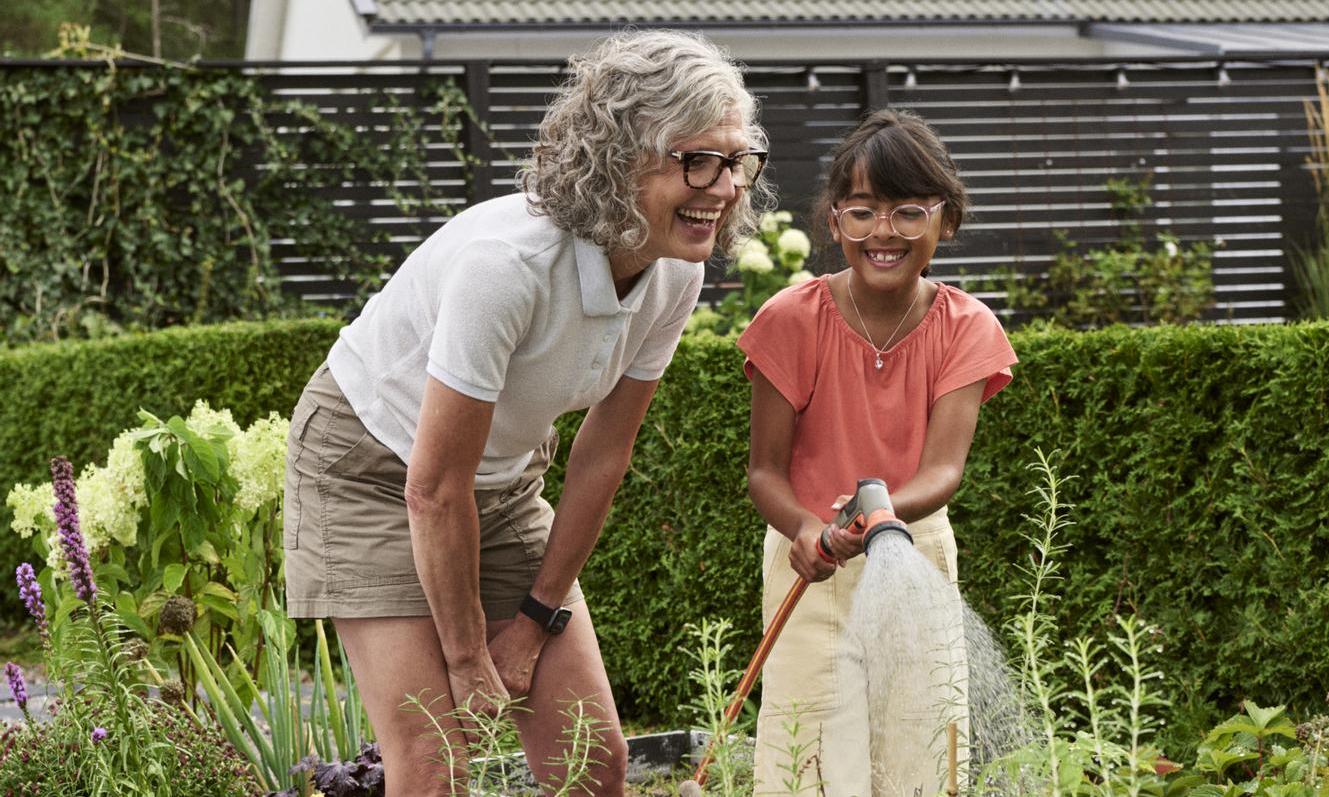 Grandmother and granddaughter watering in kitchen garden