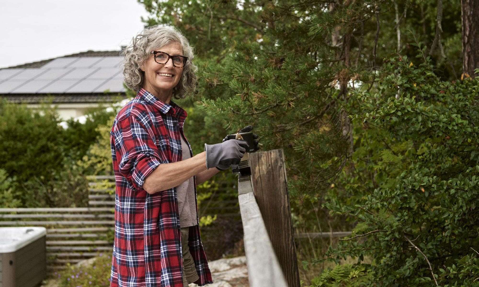 Woman oiling the fences. Solar panel in the background