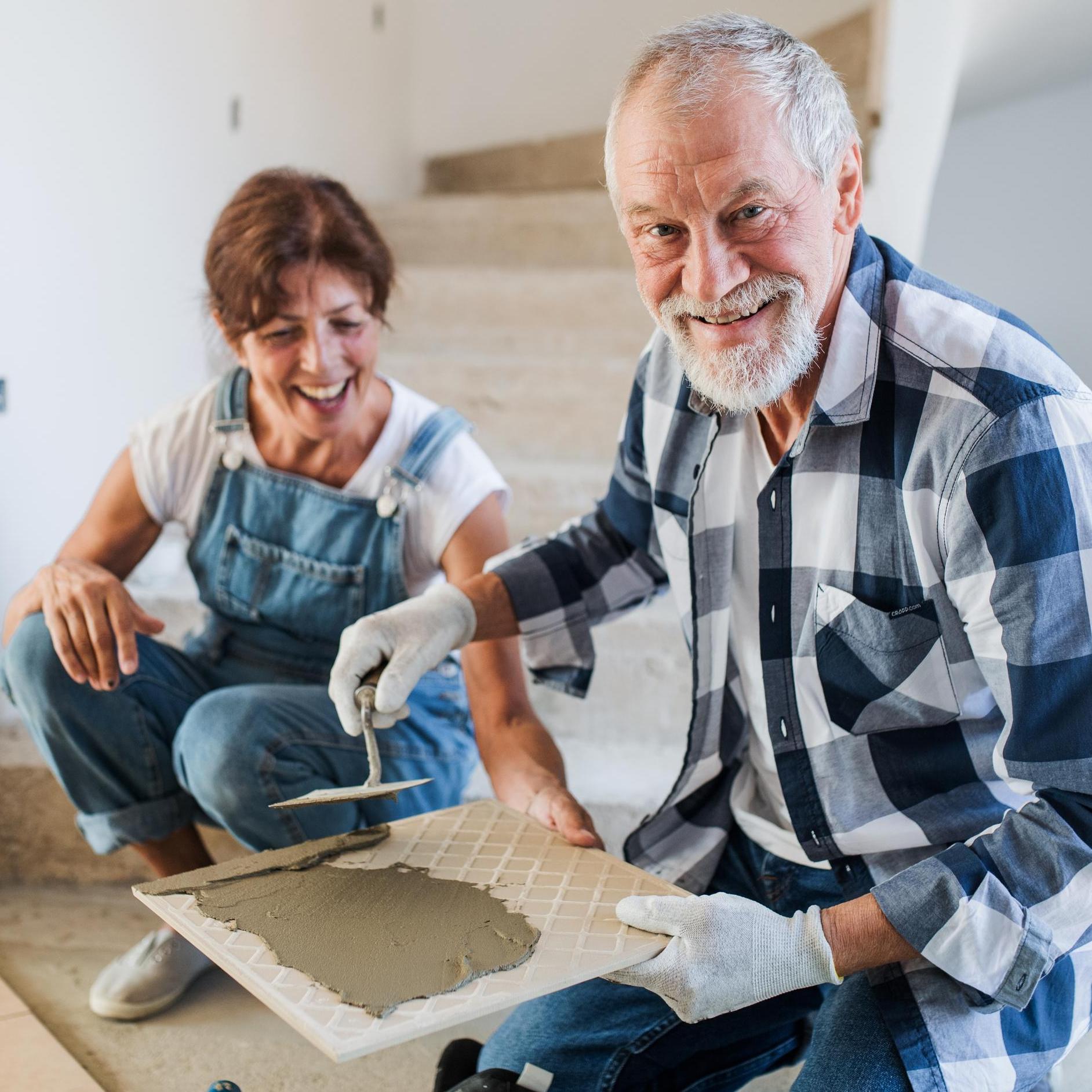 Old man and woman working on interior of new house or flat.