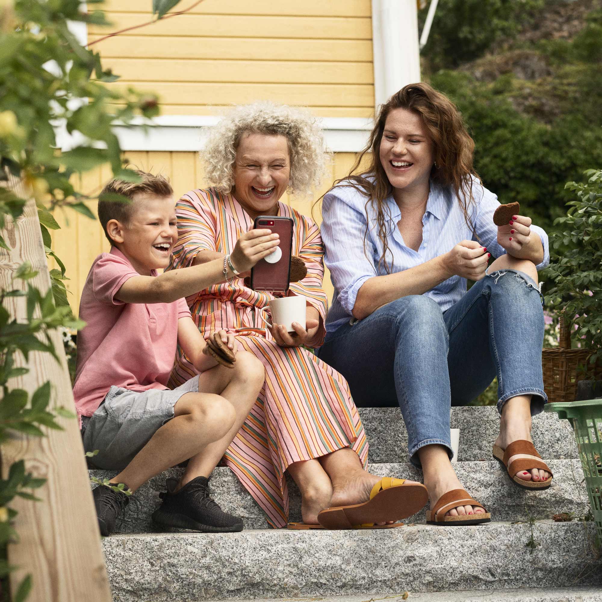 En familj sitter på trappan framför deras hus.