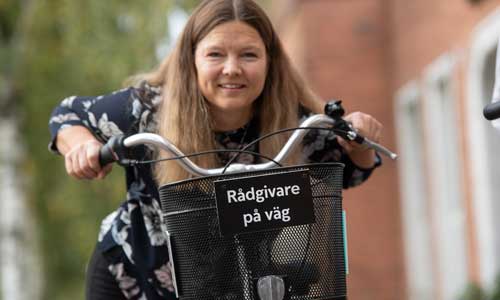 leende kvinna med cykel tittar in i kameran