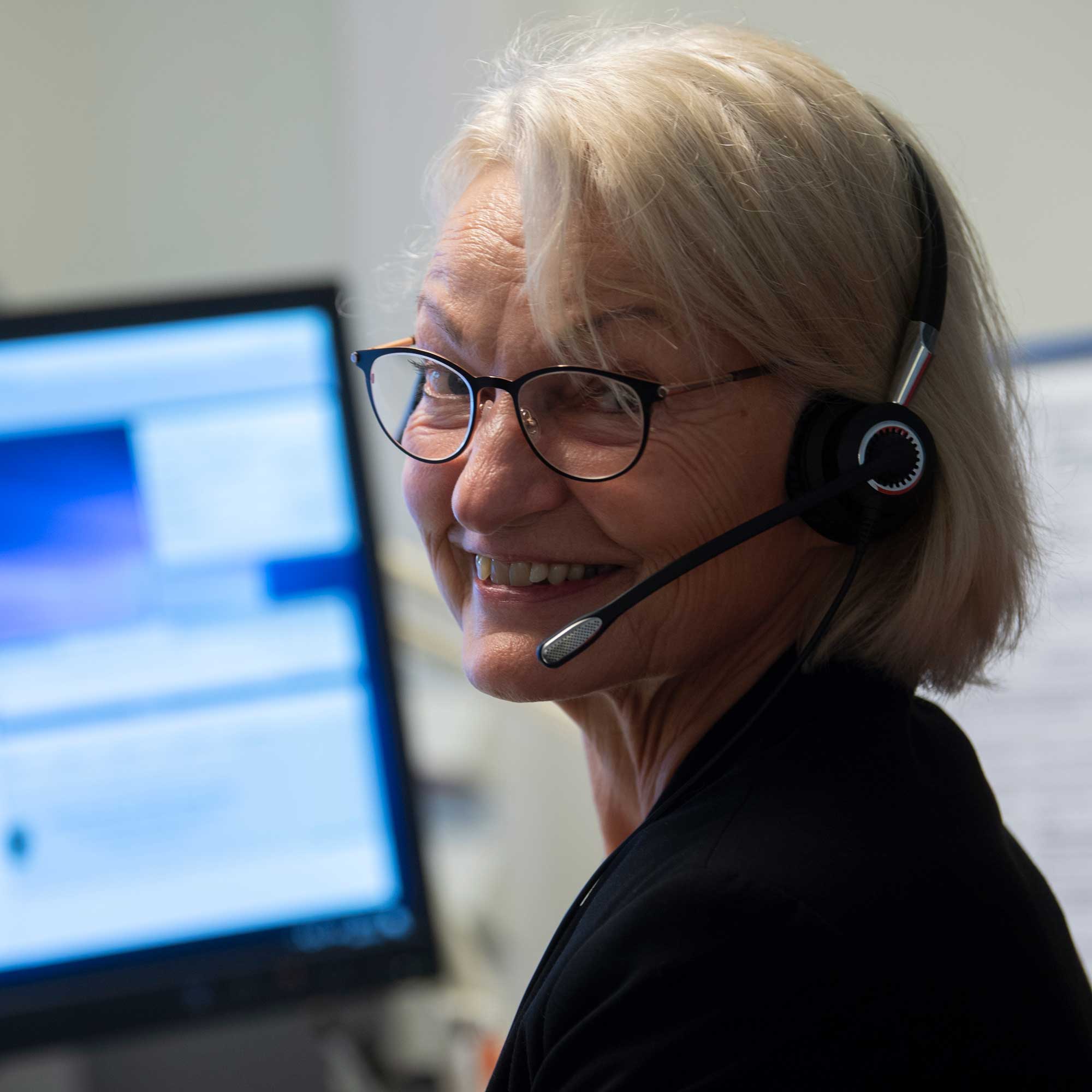 women with a headset in front of a computer